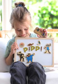 Set di giocattoli magnetici in legno con personaggi colorati e lettere su una lavagna bianca, con un bambino che tiene un personaggio. Le texture sono varie.