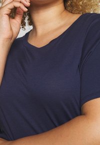 Navy blue short-sleeve top with a v-neckline, made of soft, smooth fabric; features a fitted silhouette and seamless shoulders.