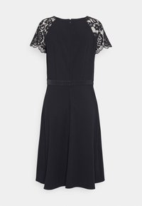 Vestido preto com corpete ajustado, saia rodada e mangas curtas de renda. O fecho nas costas e o detalhe em cetim na cintura valorizam o design.