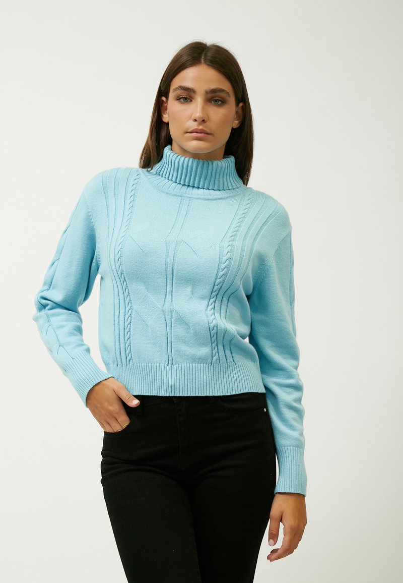 Hellblauer Rollkragenpullover mit Zopfmuster, gerippten Bündchen und Saum. Kombiniert mit schwarzen, figurbetonten Hosen. Glatte Textur, lässige Passform.