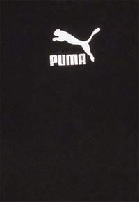 Černé tričko vyrobené z bavlněné tkaniny s bílým logem Puma. Logo zobrazuje siluetu skákající kočky nad textem "PUMA."