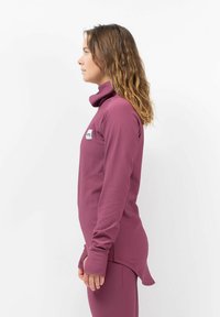 Fitted, long-sleeve purple top with a high collar, textured ribbed material, and a logo patch on the left side.