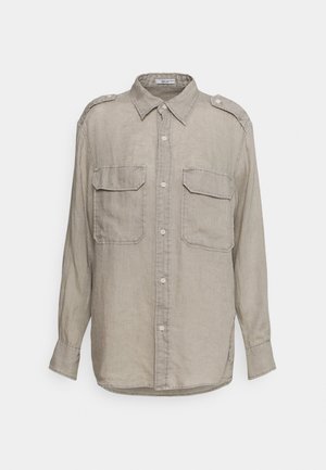 Chemise beige à manches longues boutonnée avec deux poches avant à rabat et épaulettes, en tissu léger texturé.
