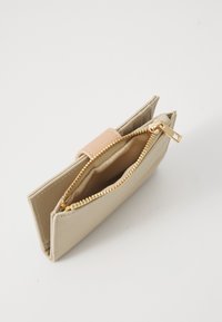 Beige glidelomme med rosa lærdetalj, utstyrt med gullfarget hardware, en glatt tekstur og rektangulær form. Åpen for synlighet.