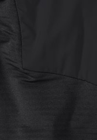 Zwart textiel met een glad, glanzend bovenste deel en een getextureerd onderste deel. De materialen lijken qua kleur op elkaar, maar verschillen in afwerking.