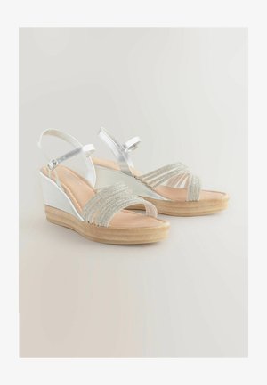 Peskasta obutev z wedge peto z srebrnimi metalnimi trakovi in perlicami, z bež notranjostjo in teksturirano gumijasto podplatom.