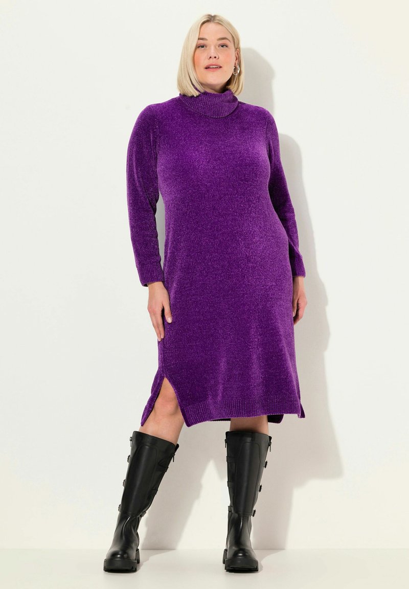 Abito a collo alto viola con un knit leggermente testurizzato, caratterizzato da spacchi laterali e maniche lunghe, abbinato a stivali neri al ginocchio.