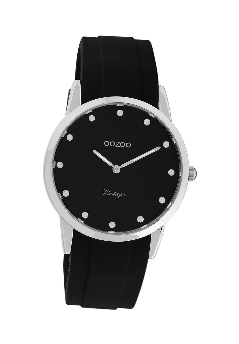 Montre avec bracelet en silicone noir, cadran noir, accents argentés et index des heures en cristal. Elle présente un design minimaliste et un boîtier en métal.