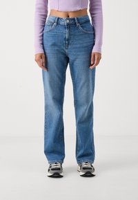 Jeans de ganga azul claro com um ajuste relaxado, apresentando uma cintura alta, design de cinco bolsos e detalhes de costura subtil.