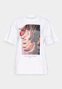 Bílý tričko s grafickým potiskem basketbalových bot a textem "Je to zcela nová hra" v modré barvě, kulatý výstřih, krátké rukávy.