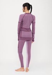 Lila mintás aktív sportöltözet szett, amely egy texturált, hosszú ujjú felsőből és a hozzá illő leggingsből áll, kontrasztos oldalsó panelekkel.