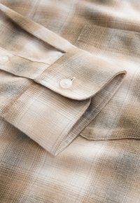 Bézs és barna kockás ing, puha anyagból készült, gombsoros elülső résszel és elegáns gallérral, sima textúrával és enyhe fényességgel.