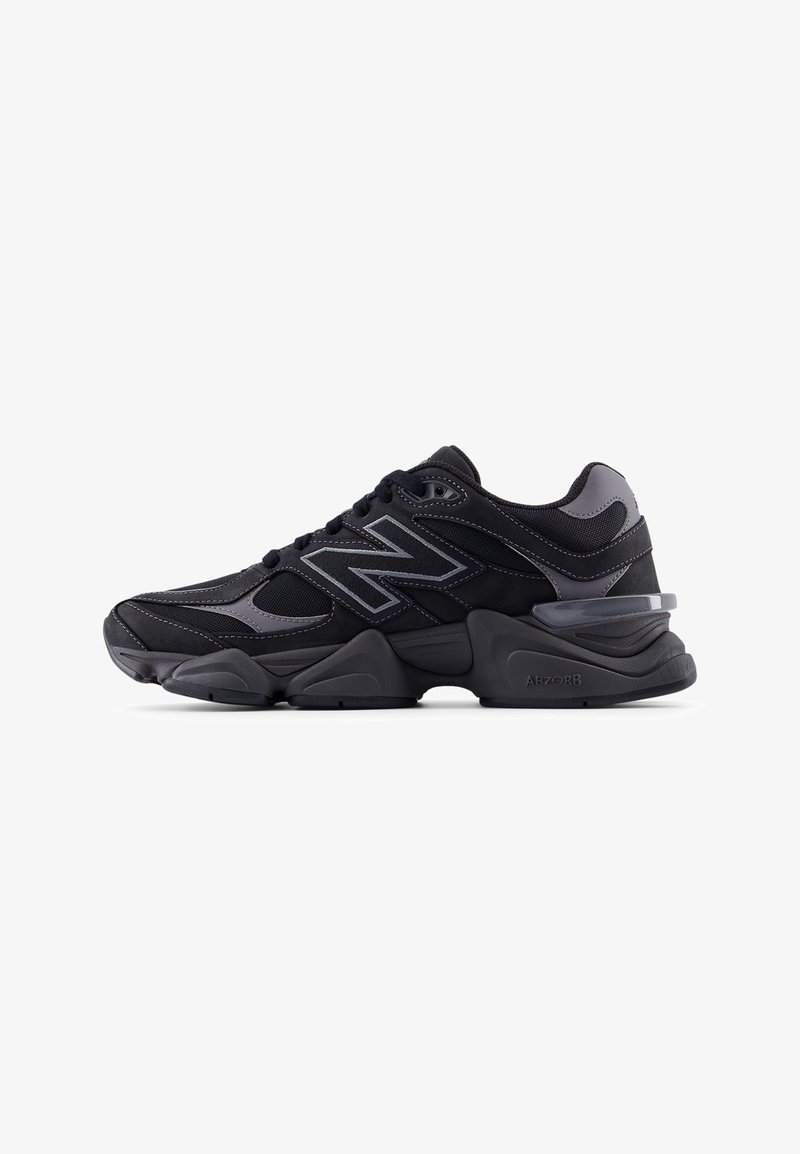 Baskets de sport noires et grises avec panneaux en mesh et cuir, fermeture à lacets, semelle épaisse rembourrée et logo estampillé sur le côté.