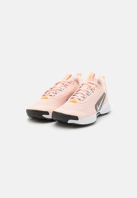 Light pink athletic shoes with textured mesh upper, contrasting black rubber outsole, and multicolored accents on laces and tongue.