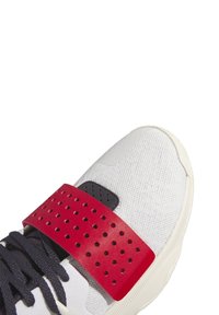 Sneaker med en vit mesh-övre, marinblå snören, röd perforerad rem och svarta detaljer. Tjock gummisula med strukturerad design.