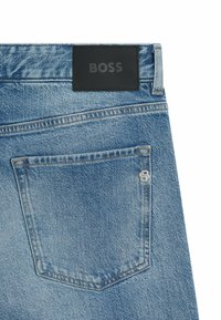 Jean en denim bleu clair avec une finition texturée. Doté d'une patch en cuir noir à la taille avec le logo "BOSS" et d'une poche arrière avec des détails de couture.