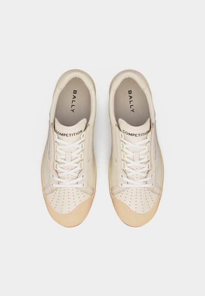 Paire de baskets Bally Competition beiges avec lacets blancs et zone perforée à l'avant, vue de dessus sur fond blanc.