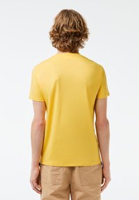 Korte mouwen gele t-shirt met een ronde halslijn, lichtgewicht stof, soepele textuur en een aansluitende snit, met minimale naden.