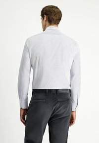 Heren overhemd met lange mouwen in het wit met blauwe verticale strepen, voorzien van een gespreid kraag en knopenmanchetten, gecombineerd met grijze corduroy broek.