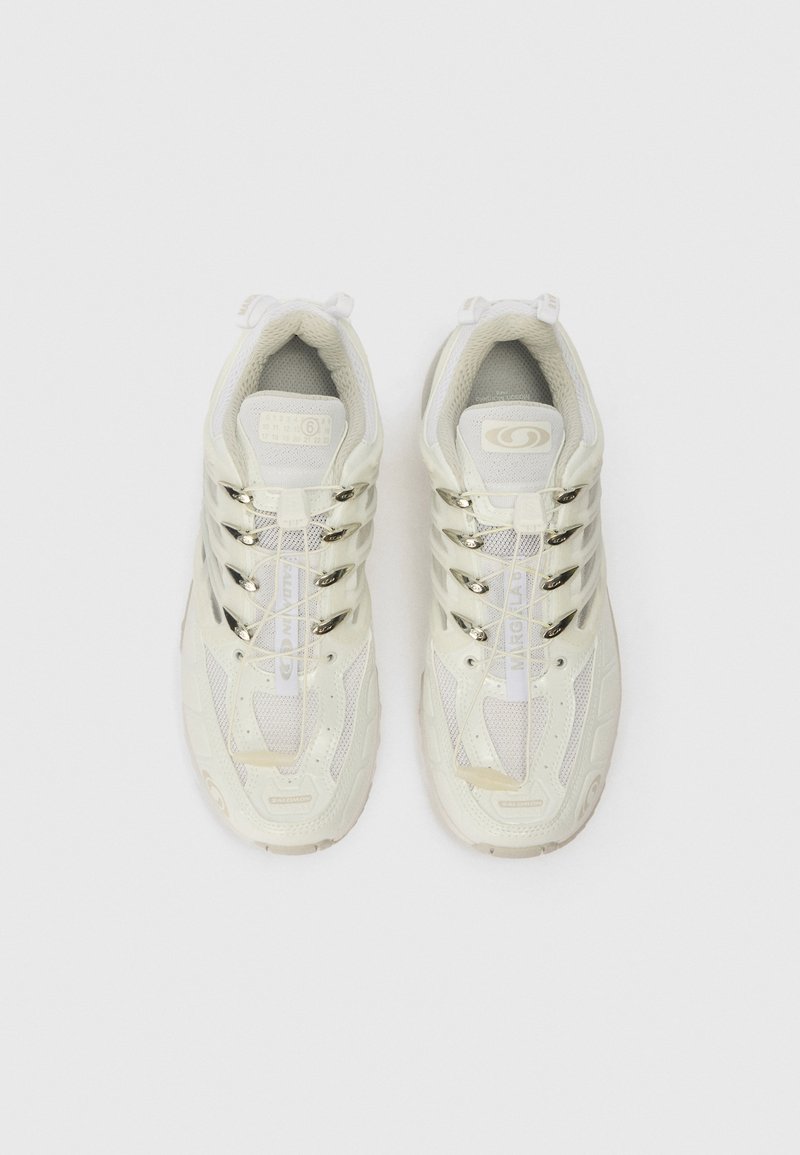 Vita sportskor med mesh-övre, reflektiva detaljer och en dämpad sula. Har ett framträdande snörningssystem och varumärkesdetaljer.