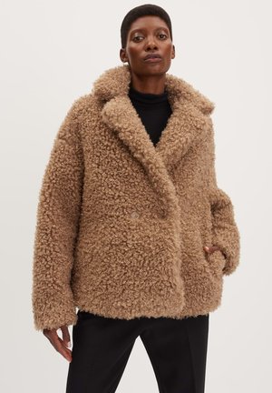 Cappotto in pelliccia sintetica marrone, con texture, dotato di ampio colletto, chiusura doppiopetto e tasche laterali; vestibilità oversize e materiale morbido e riccio.