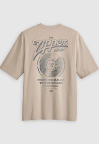 T-shirt de algodão bege com estampa gráfica apresentando o texto "Zipper Radio" e imagens de disco de vinil. Mangas curtas e decote redondo.