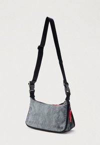 Grå skulderveske i stoff med teksturert overflate, rød glidelåsdetalj, justerbar svart stropp og teksten "FOR SUCCESSFUL LIVING" trykket i svart.