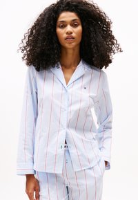 Light blue striped pajama set with red vertical lines. Features a button-up shirt with a collar and long sleeves, made from soft fabric.
