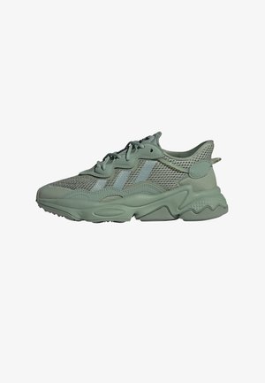 Green athletic sneaker featuring a mesh upper, rounded toe, layered design, textured details, and a multi-patterned rubber sole.