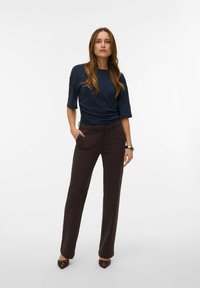 Marineblå kortermet topp med en gathered design, kombinert med mørkebrune skreddersydde bukser og brune spisse hæler.