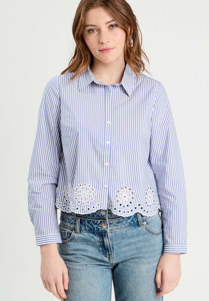 Gestreiftes Button-up-Hemd in Blau und Weiß, mit einem gewellten Saum und floralen Aussparungen. Lange Ärmel mit Manschetten, leichtes Material.