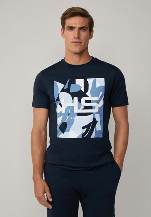 Navy blauwe katoenen t-shirt met een grote grafische afbeelding in tinten blauw en zwart met de tekst "HACKETT", korte mouwen en een ronde halslijn.