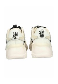 Weiße Sneakers mit schwarzen Akzenten und strukturierten Überzügen. Verfügt über eine Ziehlasche, bedruckte Initialen "SM" und eine klobige, gepolsterte Sohle.