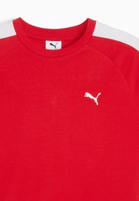 Rød bomulds t-shirt med rund hals og hvide skulderakcenter, med et lille hvidt logo på venstre brystområde.