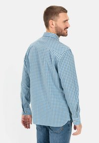 Gestreepte blauw-witte overhemd met lange mouwen en een button-down kraag, contrasterende stofstructuur en afgeronde zoom. Casual fit met knoopmanchetten.