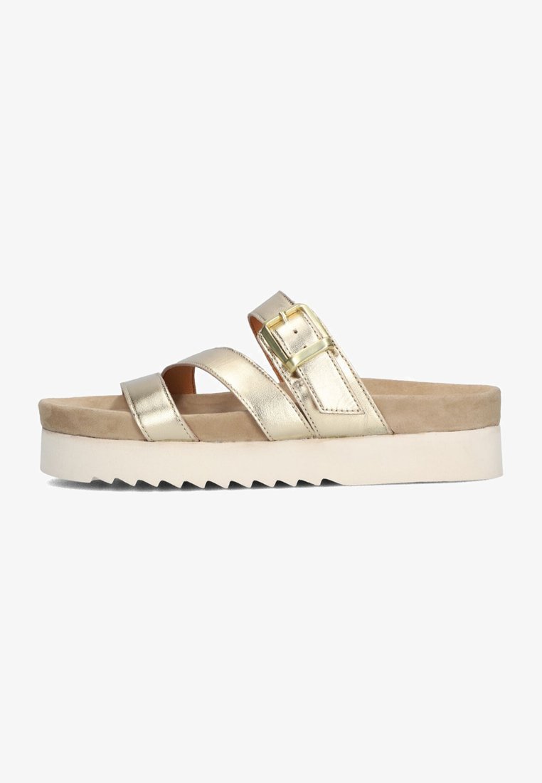 Gold metallic slide sandals with crisscross straps and buckle detail, featuring a beige cushioned insole and a white, sawtooth-patterned sole.