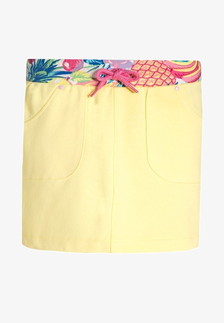 Jupe jaune avec poches avant, une ceinture à motifs tropicaux de fruits colorés, et un cordon de serrage rose au centre.