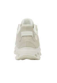 Sneaker beige e bianco visto da dietro, con un tassello a loop e una suola testurizzata progettata per la trazione.