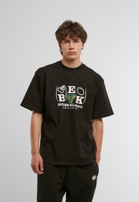Oversize sort t-shirt lavet af bomuld, med grafik på forsiden og teksten "BIS ES KLAPPT RECORDS" samt legende ikoner. Korte ærmer.