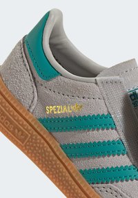 Baskets en daim gris avec des accents en cuir turquoise. Dispose de trois rayures turquoise, d'un patch en textile avec "SPEZIAL" en doré, et d'une semelle en caoutchouc brut.