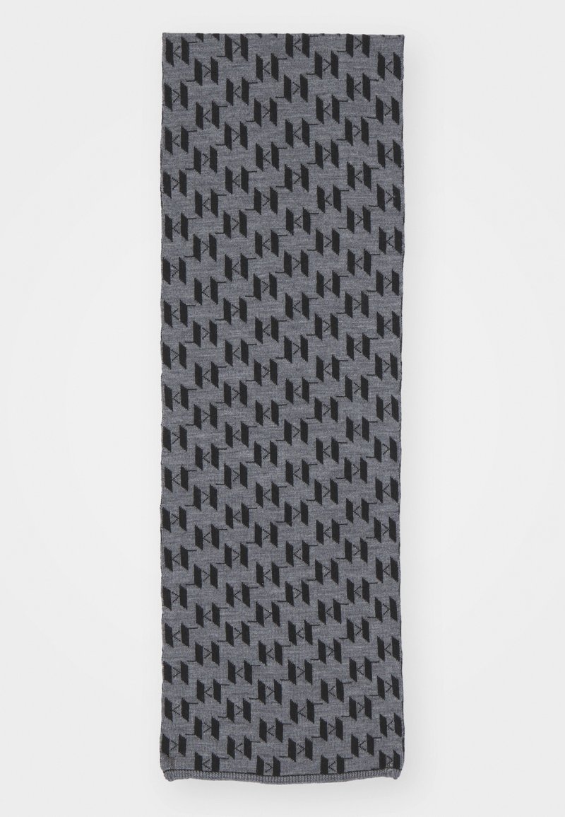 Pelēks šalle ar atkārtotu ģeometrisku rakstu melnā krāsā. Izgatavota no mīkstas auduma ar gludu tekstūru, tai ir apstrādātas malas.