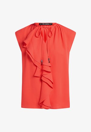 Punane pluus ümara kaelusega, millel on vasakul küljel voogav volangdetail ja nöörid. Valmistatud kergest kangast.