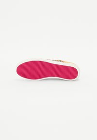 Semelle de chaussure en caoutchouc avec une base blanche texturée et un motif en relief rose vif, présentant un design supérieur coloré visible sur le bord.