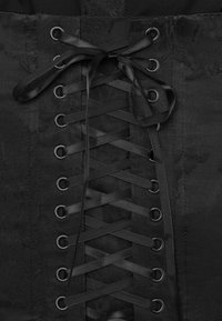 Black corset fabric with floral jacquard pattern, featuring satin ribbon lace threaded through metal eyelets tied in a bow.