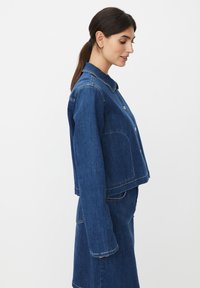 Veste en denim bleu foncé avec col, boutons sur le devant et poches latérales ; design raccourci avec détails de coutures visibles.