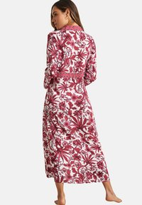 Lange bloemenrobe met een rood-wit botanisch motief, voorzien van een kraag en lange mouwen. Zachte stof met een vloeiende structuur.