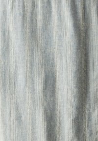 Lichtblauwe stof met verticale strepen, voorzien van verschillende texturen en stiksels, wat een subtiel maar gedefinieerd patroon creëert.