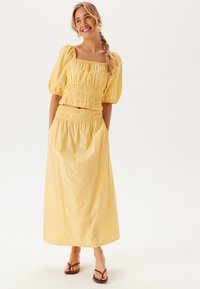 Gul maxi-kjole med puffærmer og smocket bodice. Lavet af letvægtsstof, med en afslappet pasform og sidelommer.