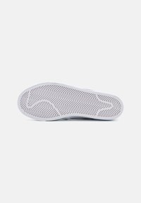 Talpa de pantof cu un model texturat, de tip herringbone, predominant alb cu accente deschise, având o construcție flexibilă din cauciuc.
