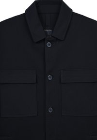 Veste noire avec un col boutonné, deux poches avant plaquées et des fermetures à boutons. Fabriquée en tissu lisse avec un design structuré.